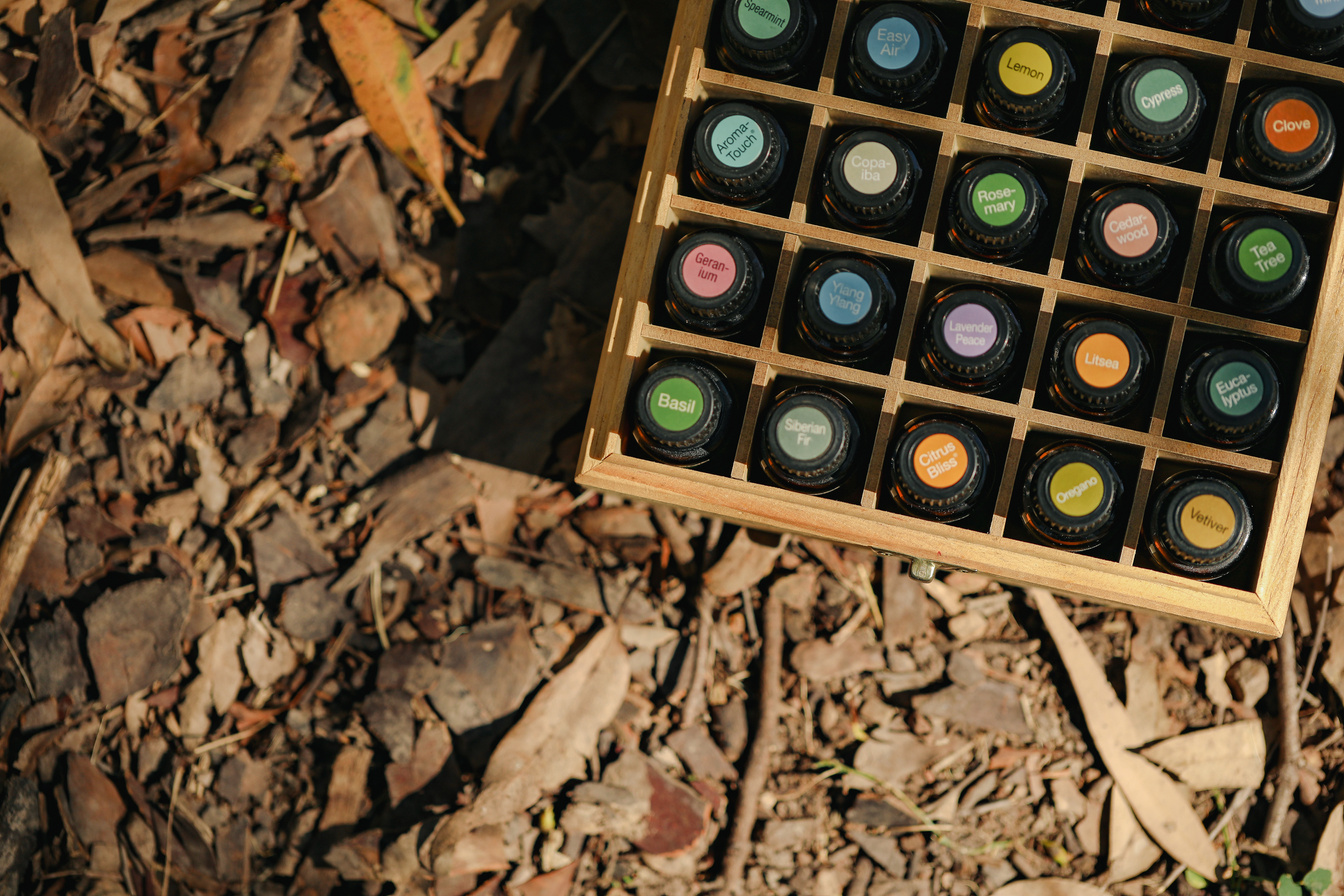 Top-down View of Essential Oil Bottles in Wooden Storage Box with Bright Colorful Cap Stickers