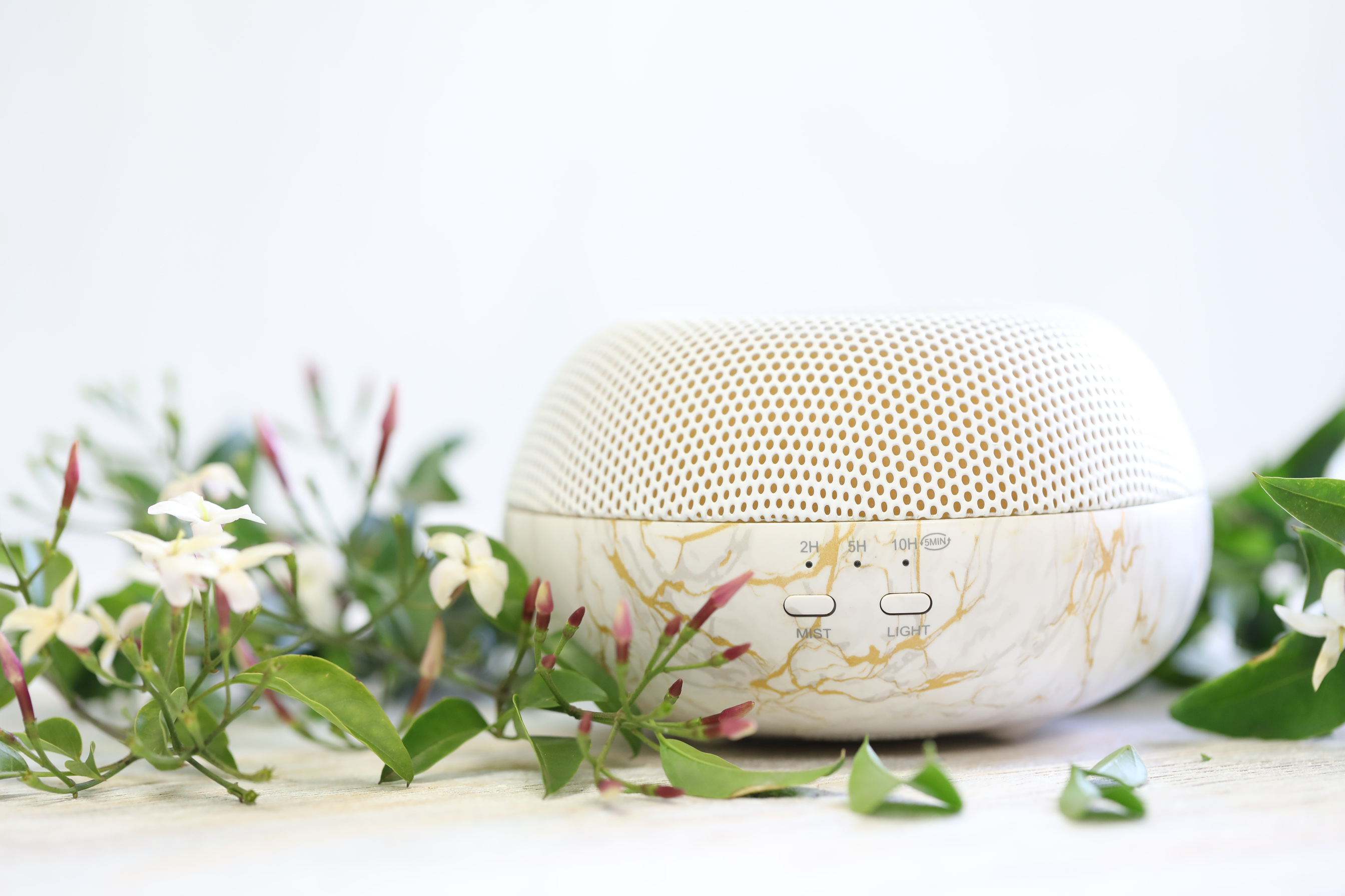 Essential oil diffuser with jasmine flowers on white background