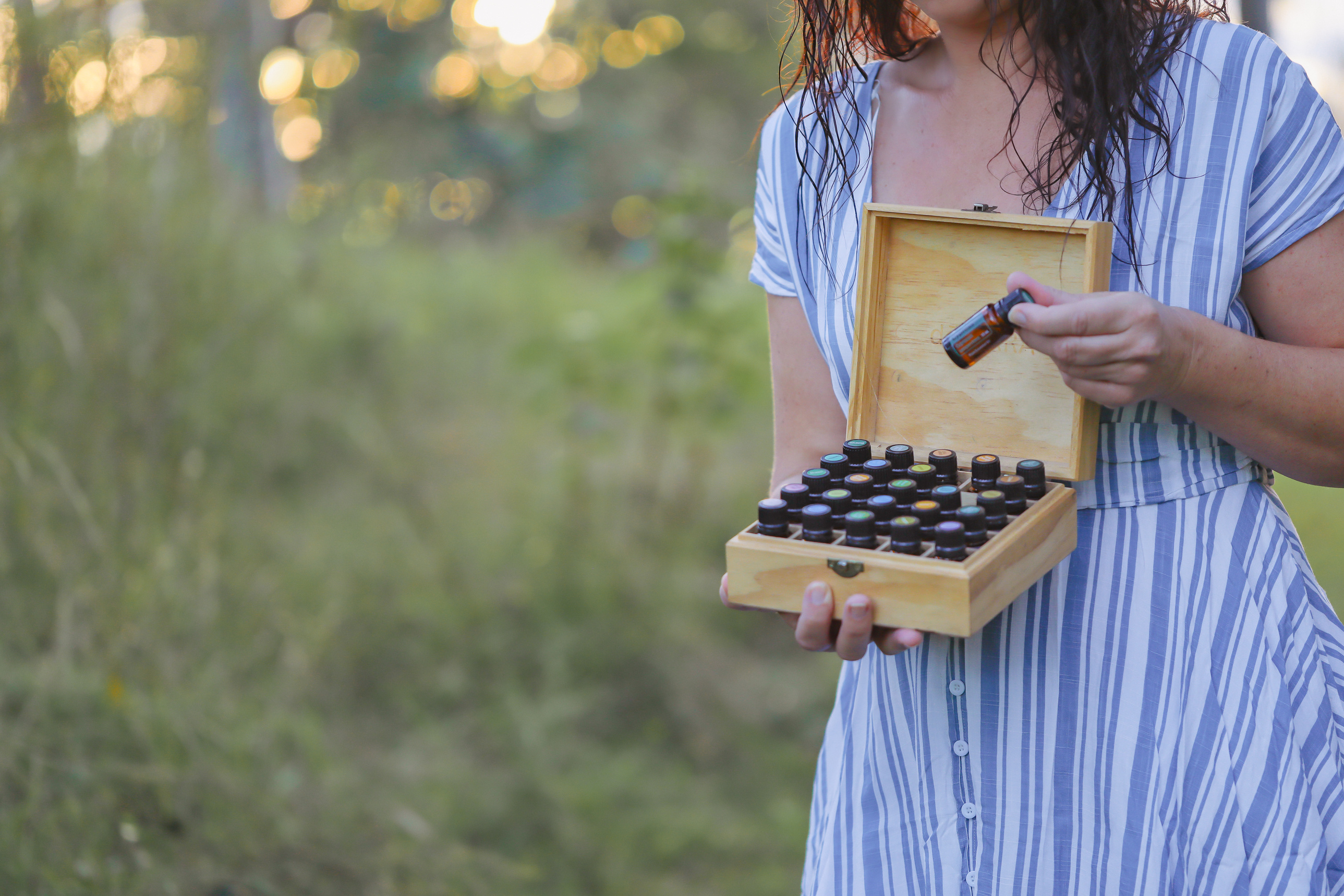 Firefly NSW Australia - 20 April 2022: Woman Standing in Field Holding Wooden Storage Box Full of Doterra Essential Oils
