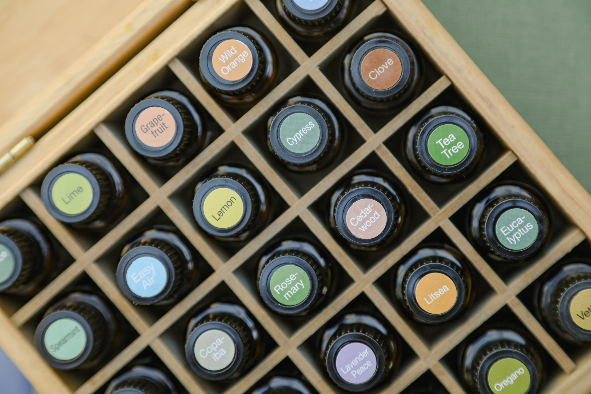 Top-down View of Essential Oil Bottles in Wooden Storage Box with Colorful Cap Stickers